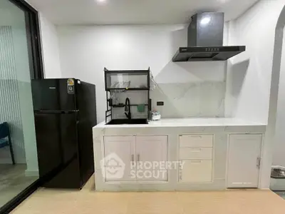 Modern kitchen with sleek black fridge and marble countertops, featuring a stylish range hood and ample storage.