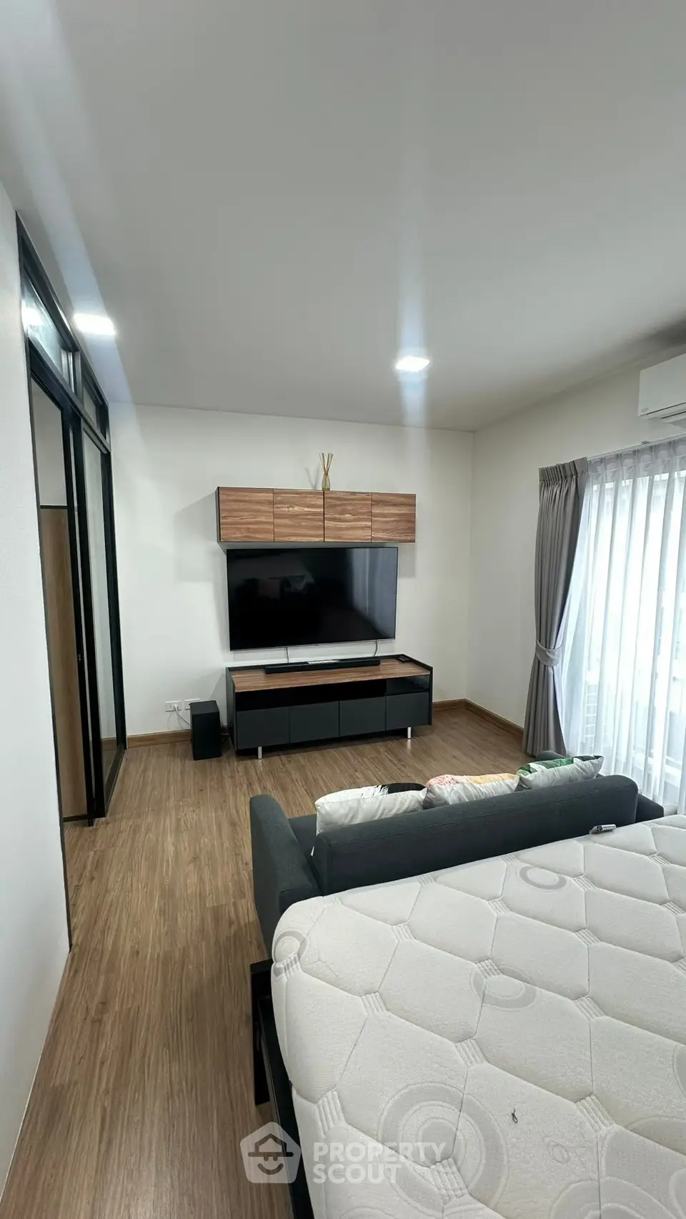 Modern living room with sleek TV unit and cozy sofa, featuring wooden flooring and natural light.