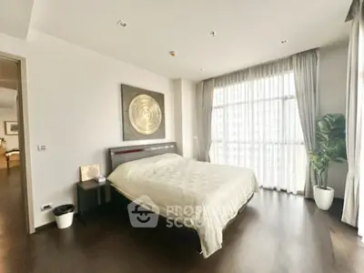 Spacious bedroom with large window and modern decor in luxury apartment.