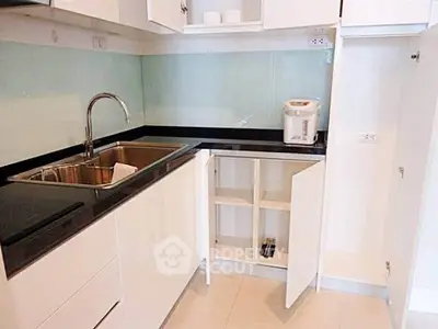 Modern kitchen with sleek white cabinets and stainless steel sink in a contemporary apartment.