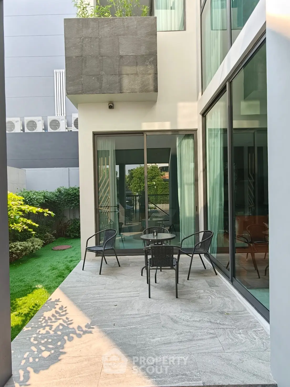 Modern patio with sleek furniture and lush greenery, perfect for outdoor relaxation.