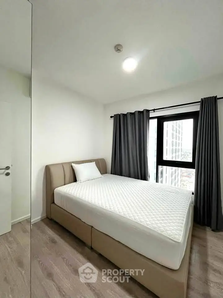 Modern bedroom with large window and stylish decor in a high-rise apartment.