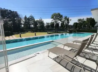 Luxurious outdoor pool area with sun loungers and lush greenery, perfect for relaxation and leisure.