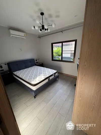 Cozy bedroom with modern lighting and air conditioning, featuring a comfortable bed and wooden flooring.