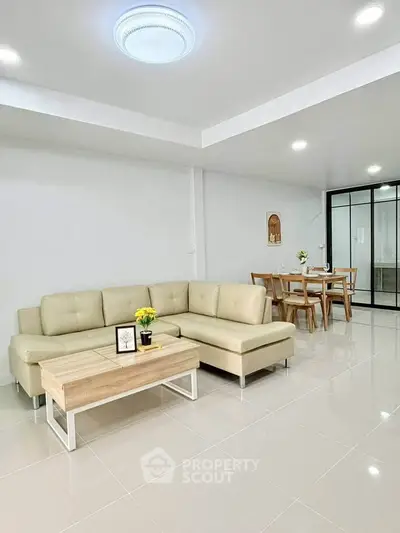 Spacious modern living room with elegant beige sofa and dining area, perfect for family gatherings.