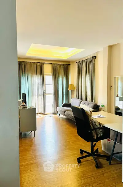 Spacious living room with modern decor and natural light, featuring a cozy sofa and work desk.