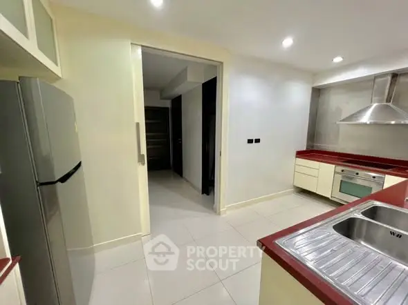Modern kitchen with sleek design, featuring stainless steel appliances and red countertops.