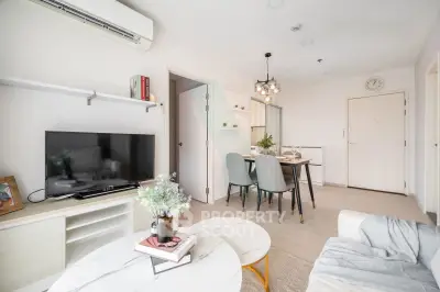 Modern living room with dining area, featuring stylish decor and natural light.