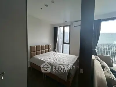 Spacious bedroom with large window and cozy bed in modern apartment