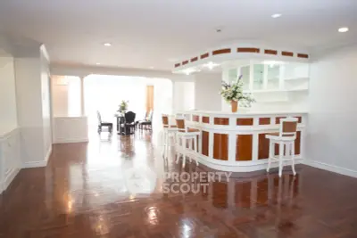Spacious open-plan living and dining area with elegant wooden flooring and stylish bar counter.
