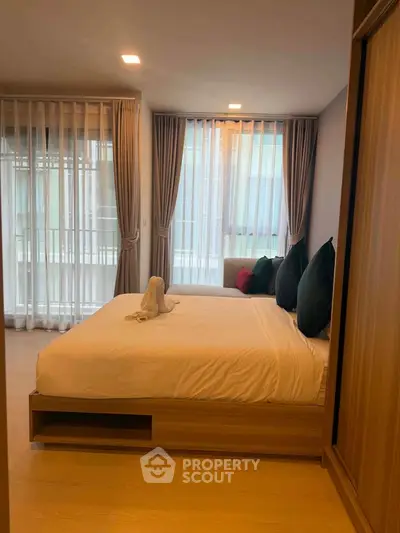 Spacious bedroom with large windows and elegant curtains in modern apartment.