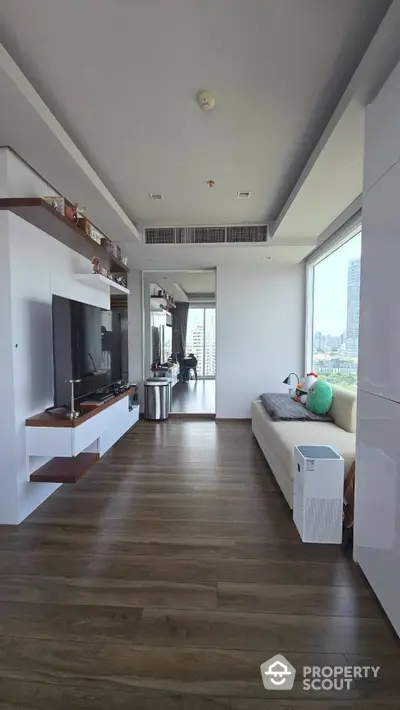 Modern living room with city view, sleek furniture, and wooden flooring in a high-rise apartment.