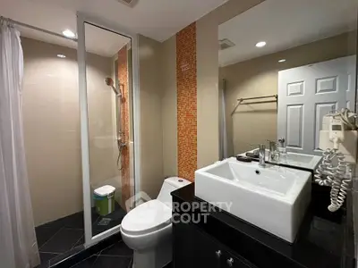 Modern bathroom with glass shower and sleek sink in stylish apartment.