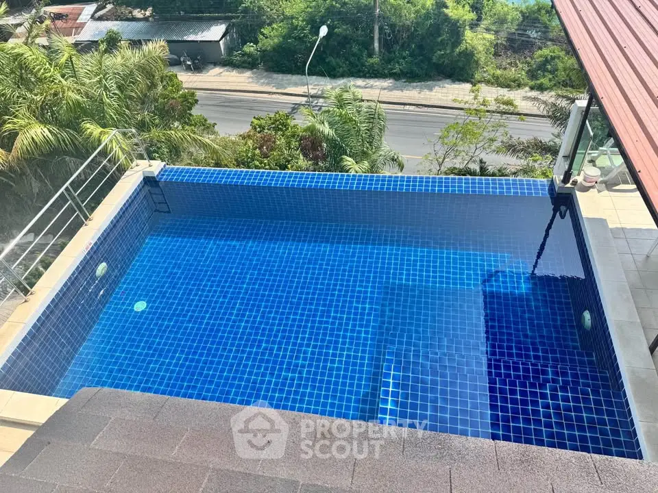 Stunning rooftop pool with lush greenery and street view, perfect for relaxation and entertainment.