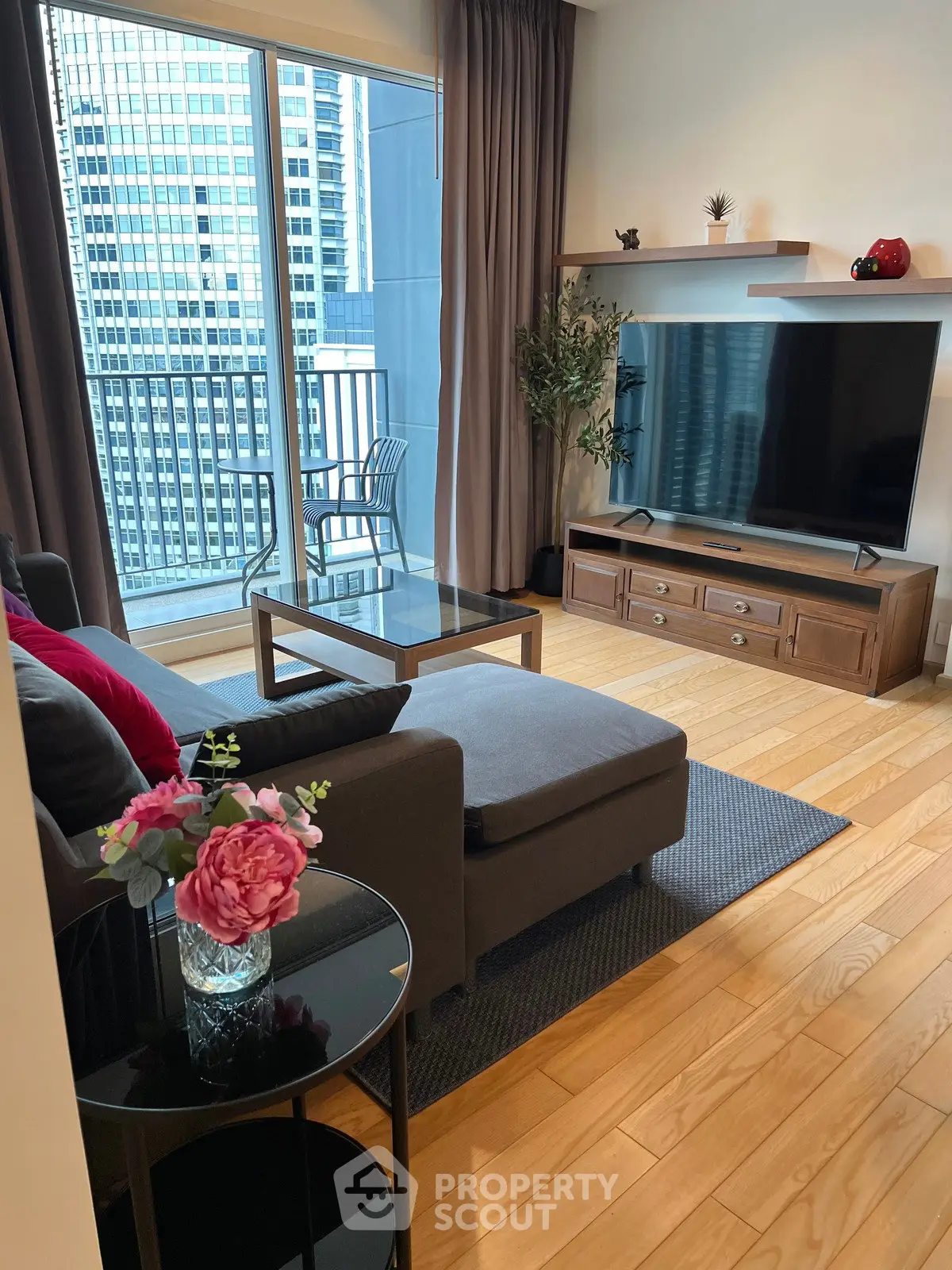 Modern living room with large TV and balcony view in urban apartment