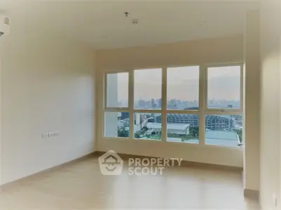 Spacious room with large windows offering stunning city skyline views.
