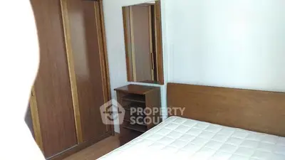 Cozy bedroom with wooden furniture and a comfortable mattress, perfect for restful nights.
