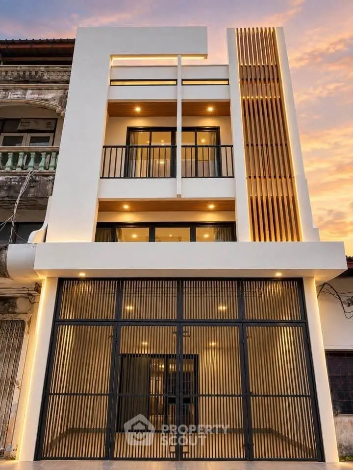 Modern three-story building with sleek facade and warm lighting at sunset.