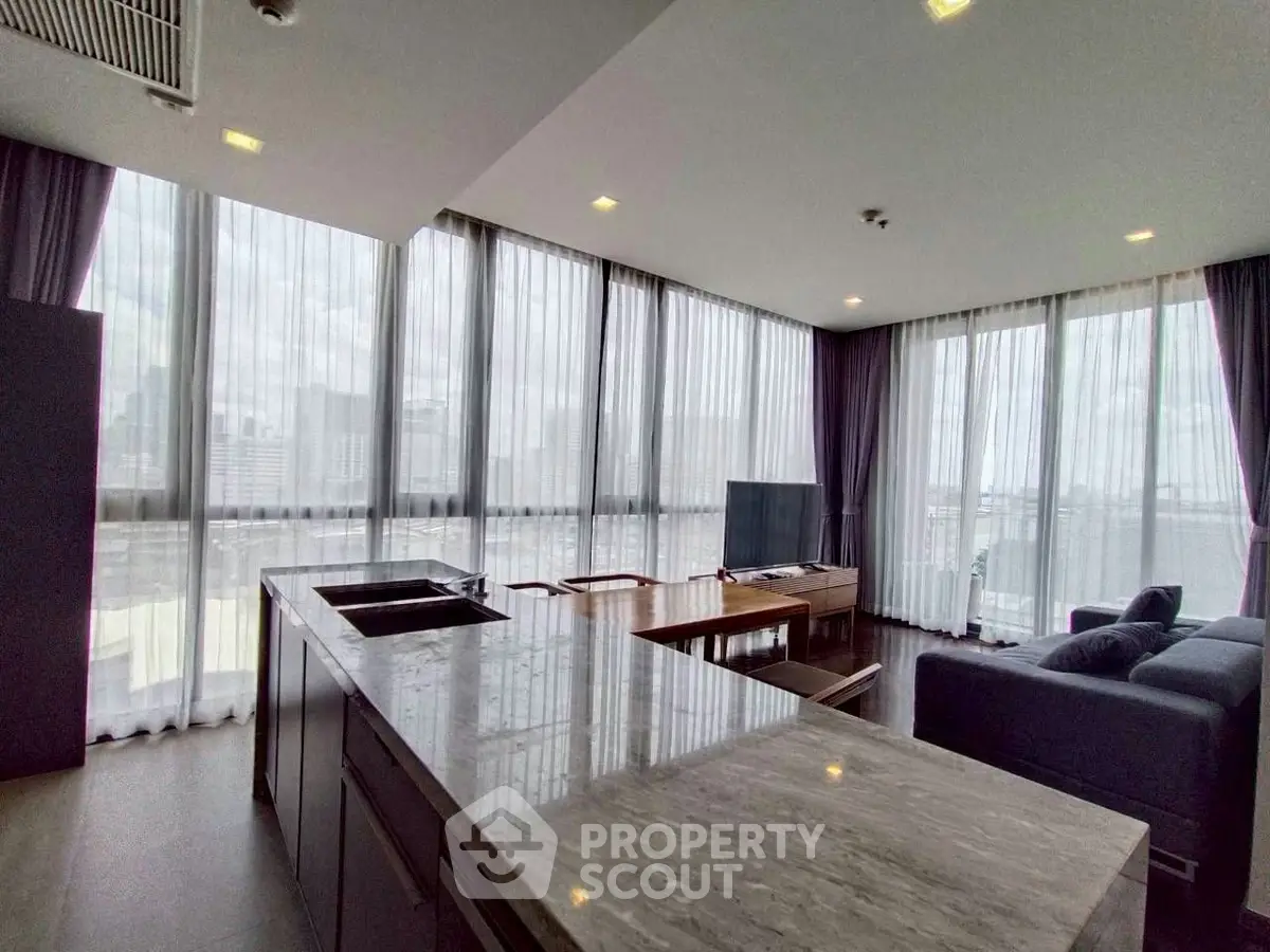 Spacious modern living room with panoramic city views and sleek kitchen island.