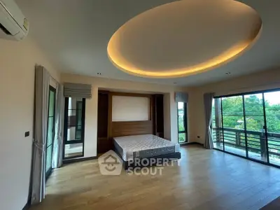 Spacious bedroom with modern lighting and large windows offering scenic views.