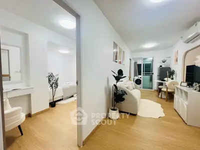 Modern apartment interior with open living room and bedroom, featuring stylish decor and wooden flooring.