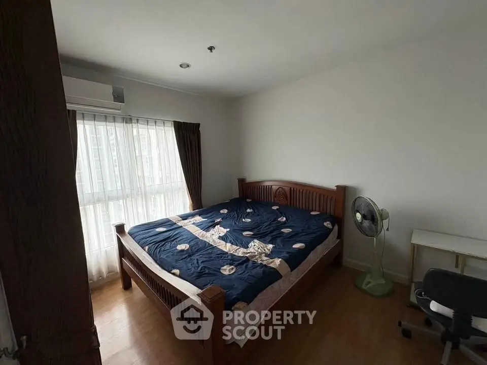 Spacious bedroom with wooden bed frame and natural light from large window.