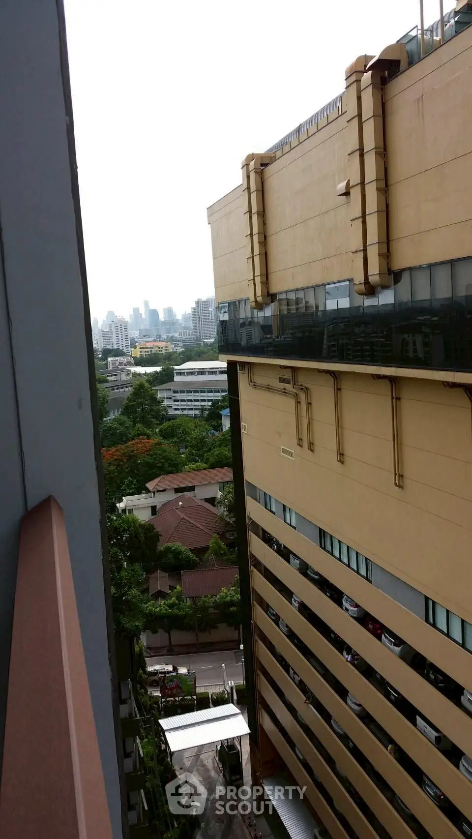 Urban building exterior with city skyline view from high floor balcony.