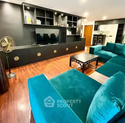 Spacious living room with modern teal sofas and sleek black entertainment unit.