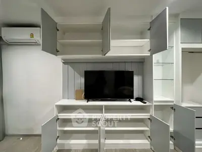 Modern living room with built-in storage and TV unit, featuring open cabinets and sleek design.