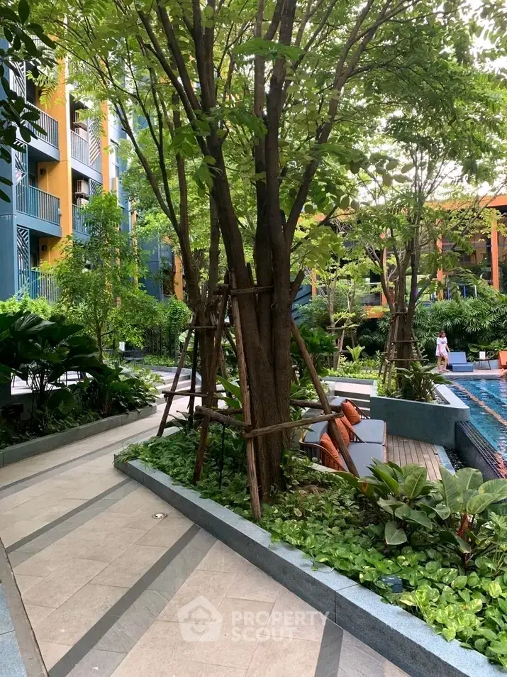 Lush garden area with poolside seating in modern residential complex
