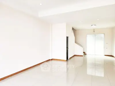 Spacious empty room with bright white tiles and staircase, ideal for customization.