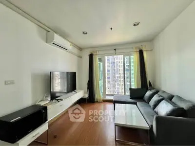 Modern living room with large window and city view, featuring sleek furniture and wooden flooring.