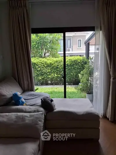 Cozy living room with plush sofa and garden view through large window.