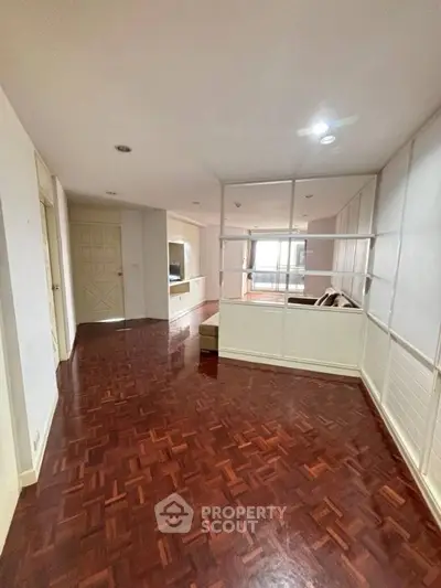 Spacious living area with wooden flooring and partition wall, ideal for modern living.