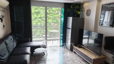 Modern living room with sleek furniture and balcony view, featuring a large TV and stylish decor.