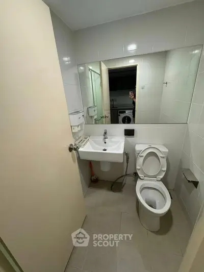 Compact bathroom with modern fixtures and washing machine in view, ideal for urban living.