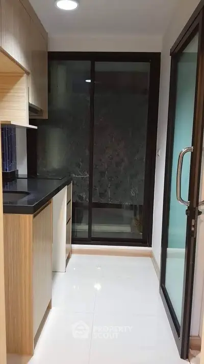 Modern compact kitchen with sleek cabinetry and large glass door for natural light.