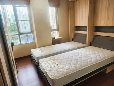 Cozy bedroom with twin beds and large windows offering natural light.