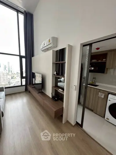Modern living room with city view, sleek furniture, and adjacent kitchen in a high-rise apartment.