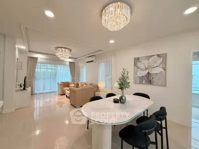 Elegant living room with modern chandelier and open dining area in luxurious home.