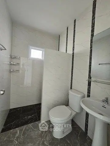 Modern bathroom with sleek design and elegant tile work, featuring a toilet, sink, and shower area.