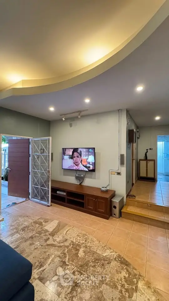 Spacious living room with modern decor and open entrance, perfect for relaxation.