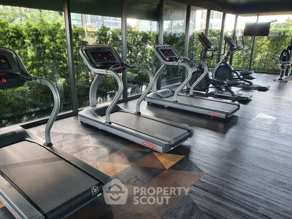 Modern gym facility in a residential building with state-of-the-art treadmills overlooking lush greenery, perfect for fitness enthusiasts.