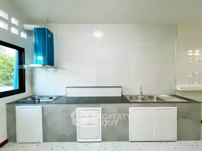 Modern kitchen with sleek design, featuring a gas stove and stainless steel sink, perfect for culinary enthusiasts.