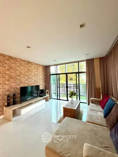 Spacious living room with modern decor and large windows offering natural light and garden view.