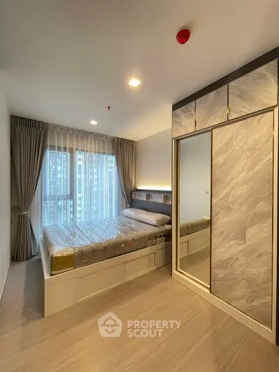 Modern bedroom with large window and stylish sliding wardrobe in a high-rise apartment.