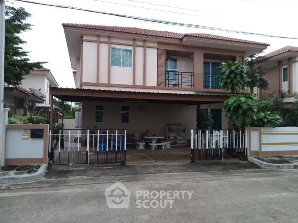 Charming two-story house with gated driveway and lush greenery in suburban neighborhood.