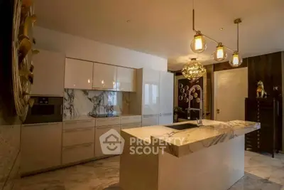 Luxurious modern kitchen with marble island and elegant lighting fixtures.