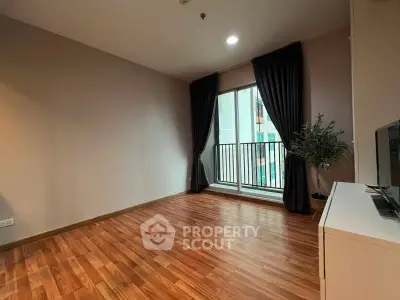 Spacious living room with wooden flooring and balcony access in modern apartment.