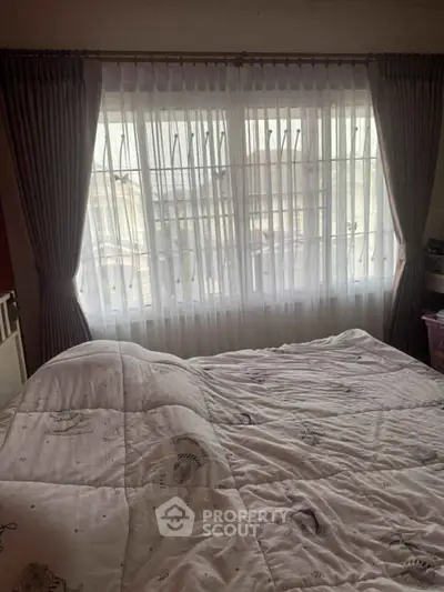 Cozy bedroom with large window and elegant curtains, perfect for natural light lovers.